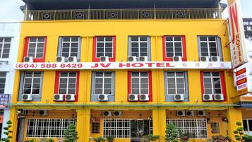 Un hotel con fachada amarilla, marcos de ventanas rojos y varias unidades de aire acondicionado.