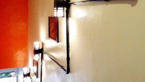 Un couloir avec un mur rouge, une photographie en noir et blanc encadrée et un luminaire.
