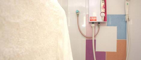 A bathroom with a towel hanging on the wall, a showerhead, and a control panel.