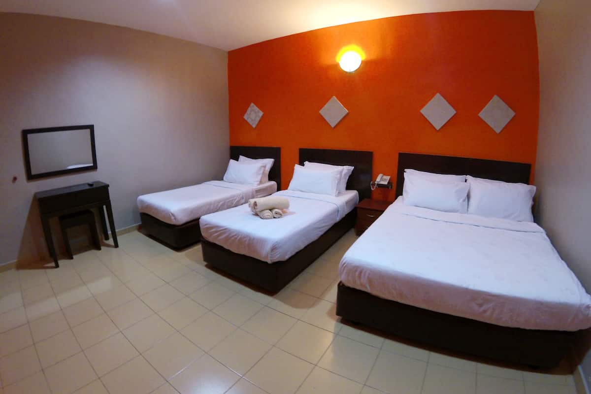 Ein Hotelzimmer mit drei Einzelbetten, einem kleinen Tisch und einem an der Wand befestigten Telefon.