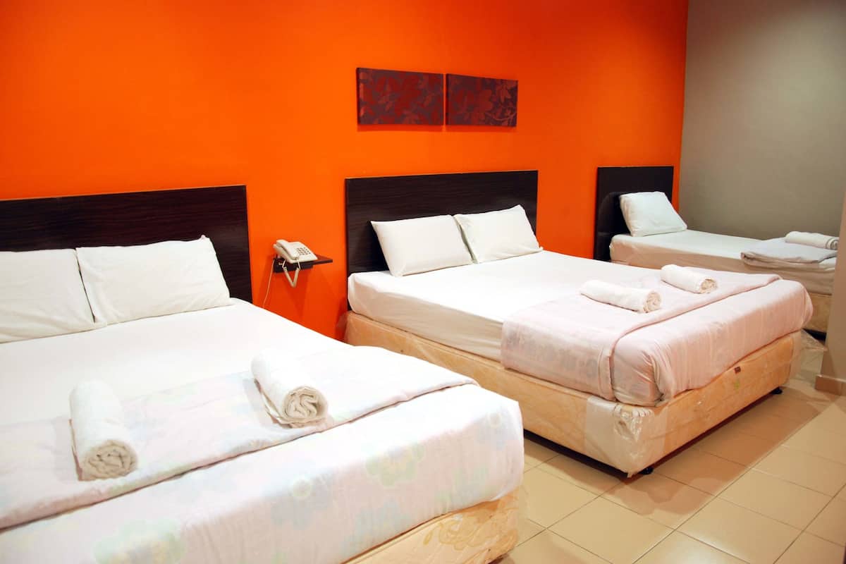 Ein Hotelzimmer mit zwei Betten, jeweils mit weißen Laken und Handtüchern, einem Holz-Kopfteil und einer orangefarbenen Wand.