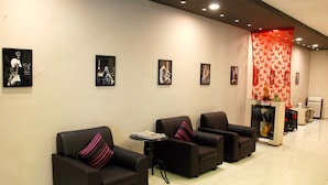 A lobby with four black armchairs, a small table with magazines, and framed pictures on the wall.