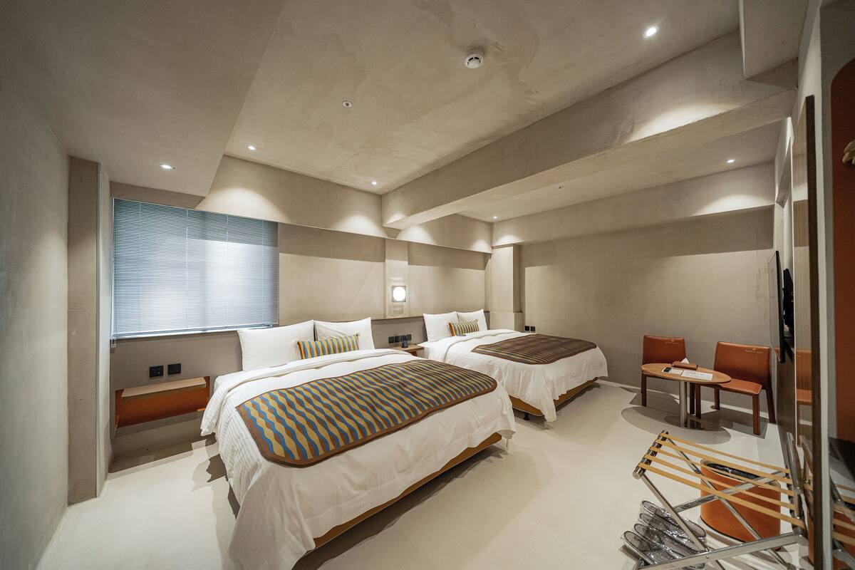 Una habitación de hotel moderna con dos camas, un área de descanso y un televisor.