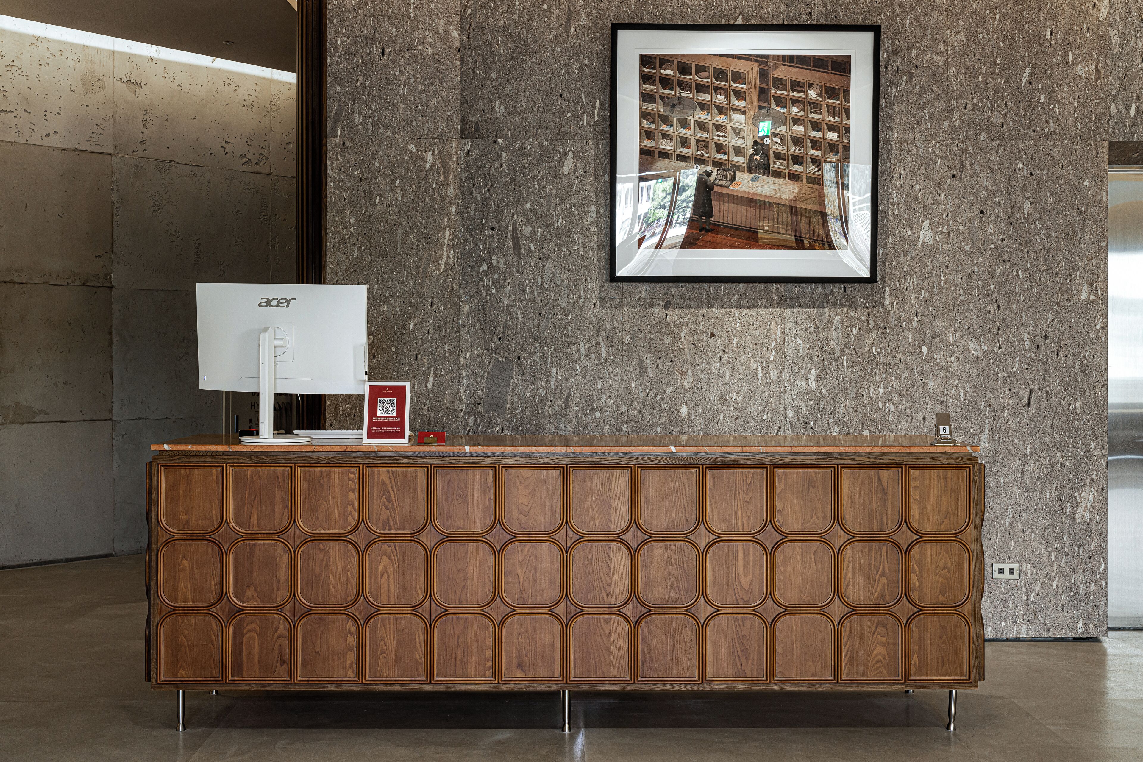 A reception desk with a wooden finish and a framed picture on the wall.