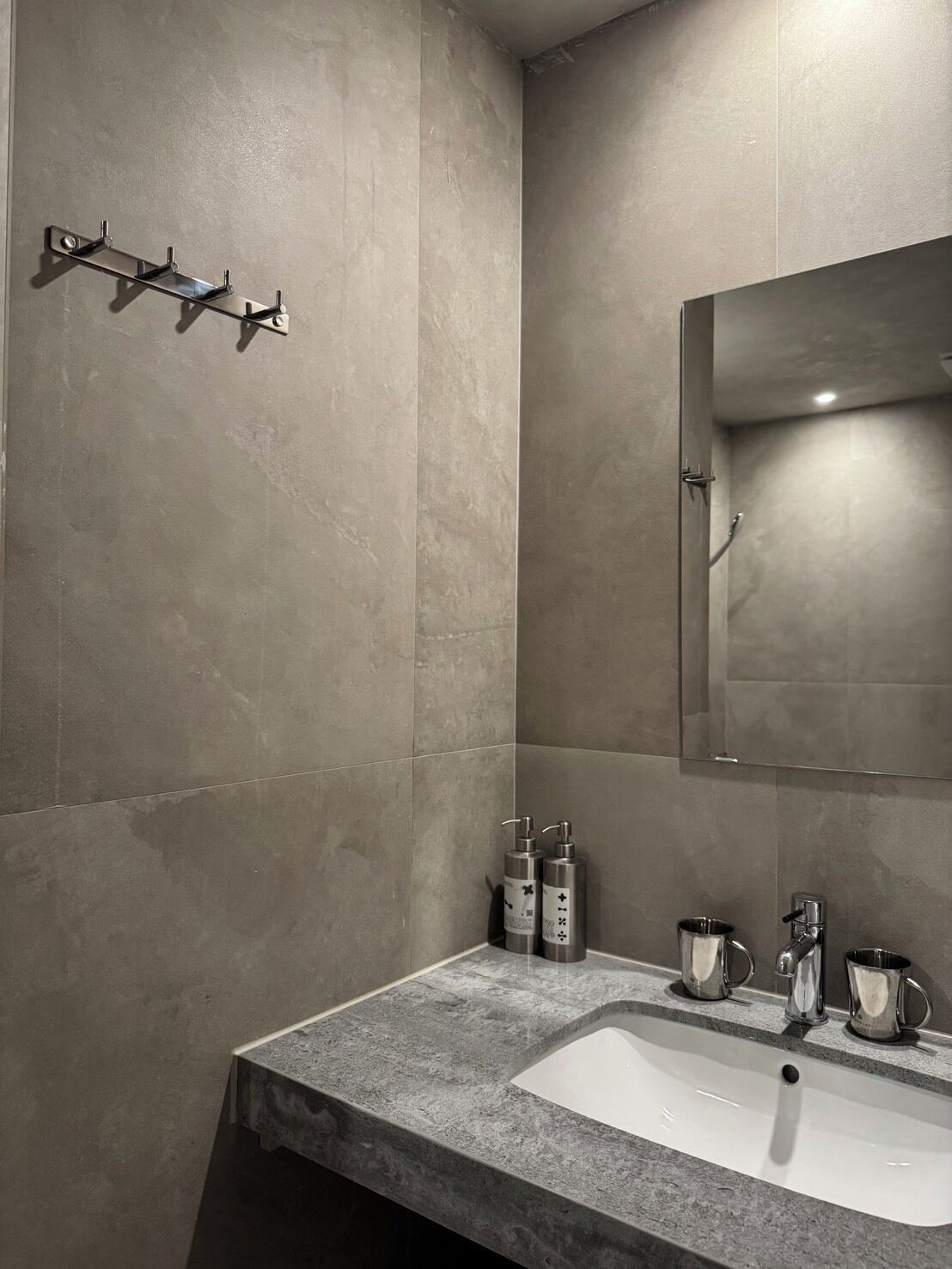 A modern bathroom with a large mirror, a sink, and a shower area.