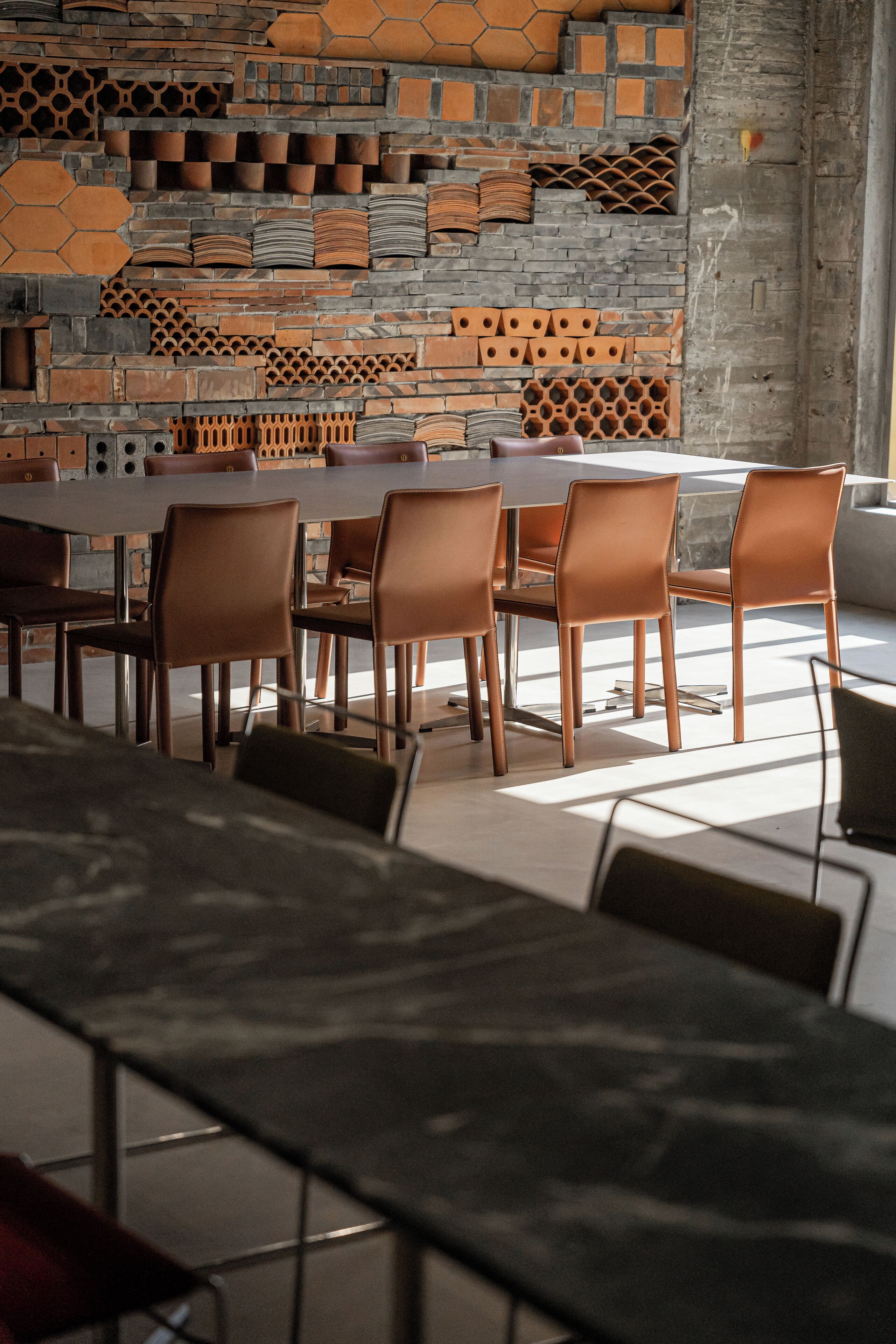A modern dining area with a brick wall and a long table with chairs.
