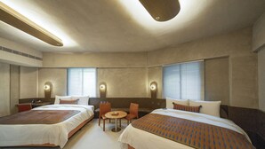 Quarto de hotel com duas camas, uma mesa pequena e duas cadeiras. Possui duas janelas com persianas e design moderno com cores neutras.
