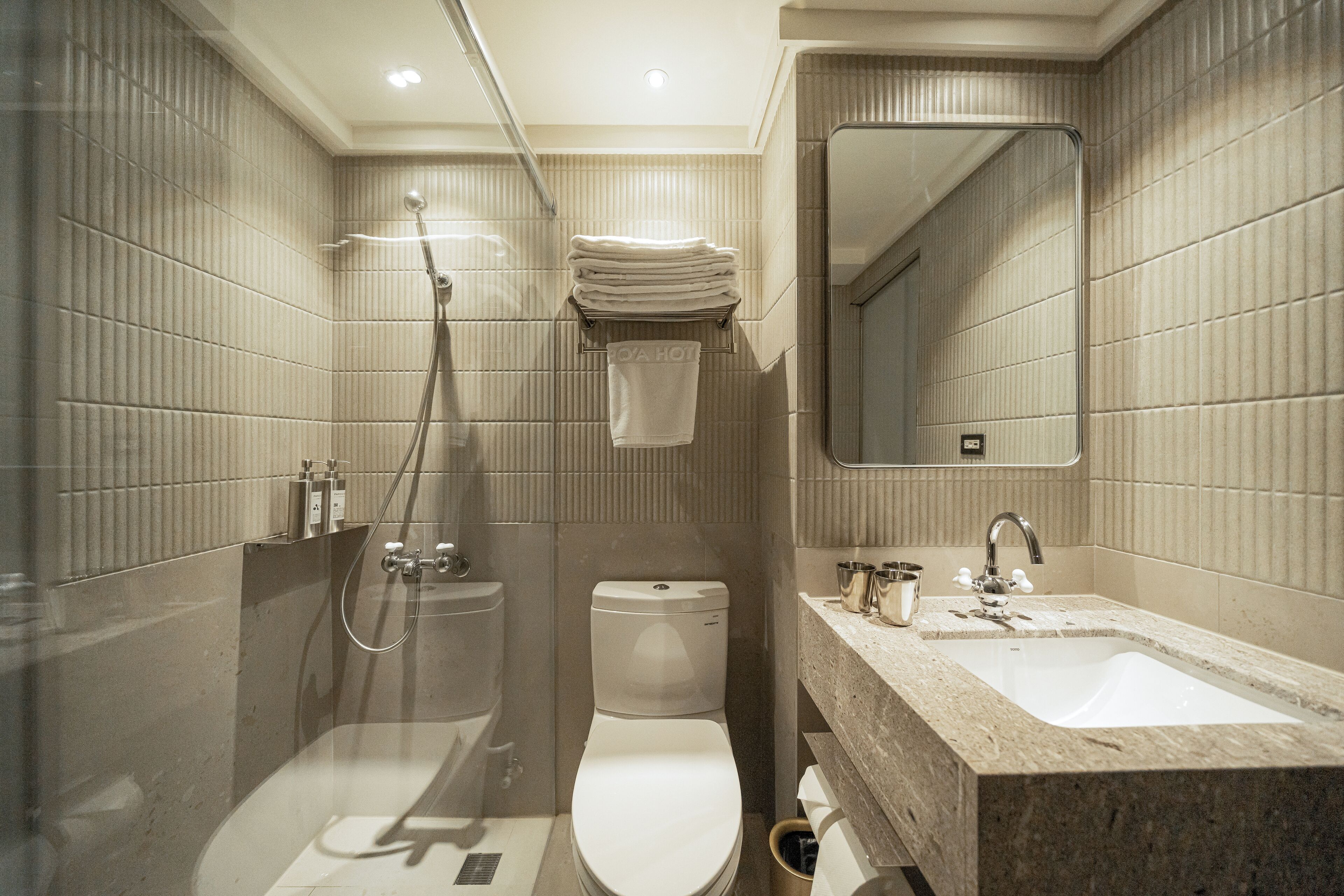 A modern bathroom with a glass-enclosed shower, a toilet, and a sink with a mirror above it.