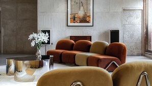 Uma sala de estar moderna com um sofá modular, uma mesa de centro e uma obra de arte emoldurada na parede.