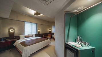 A hotel room with a large bed, a desk, a chair, a small table, and a green wall.