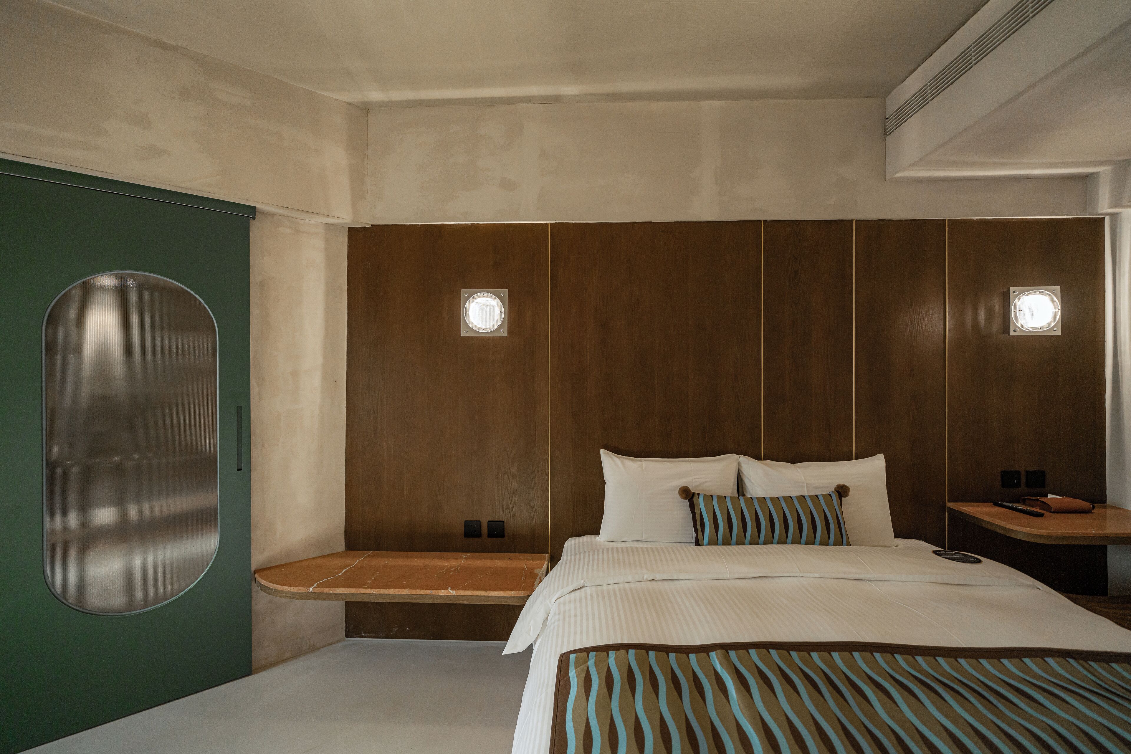 A modern hotel room with a large bed, a bench, and two bedside tables.