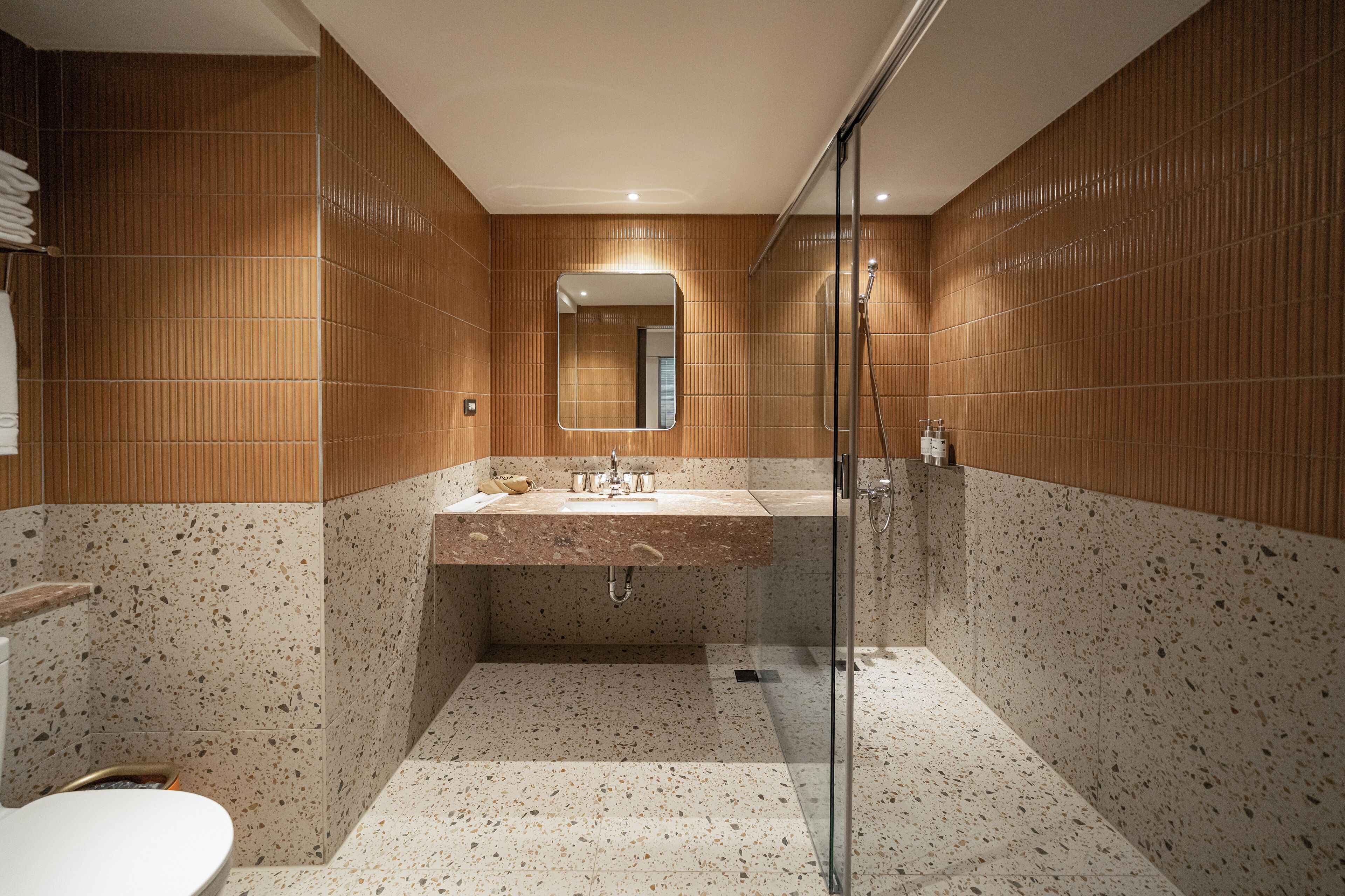 A modern bathroom with a glass shower enclosure, a freestanding sink, and a large mirror.