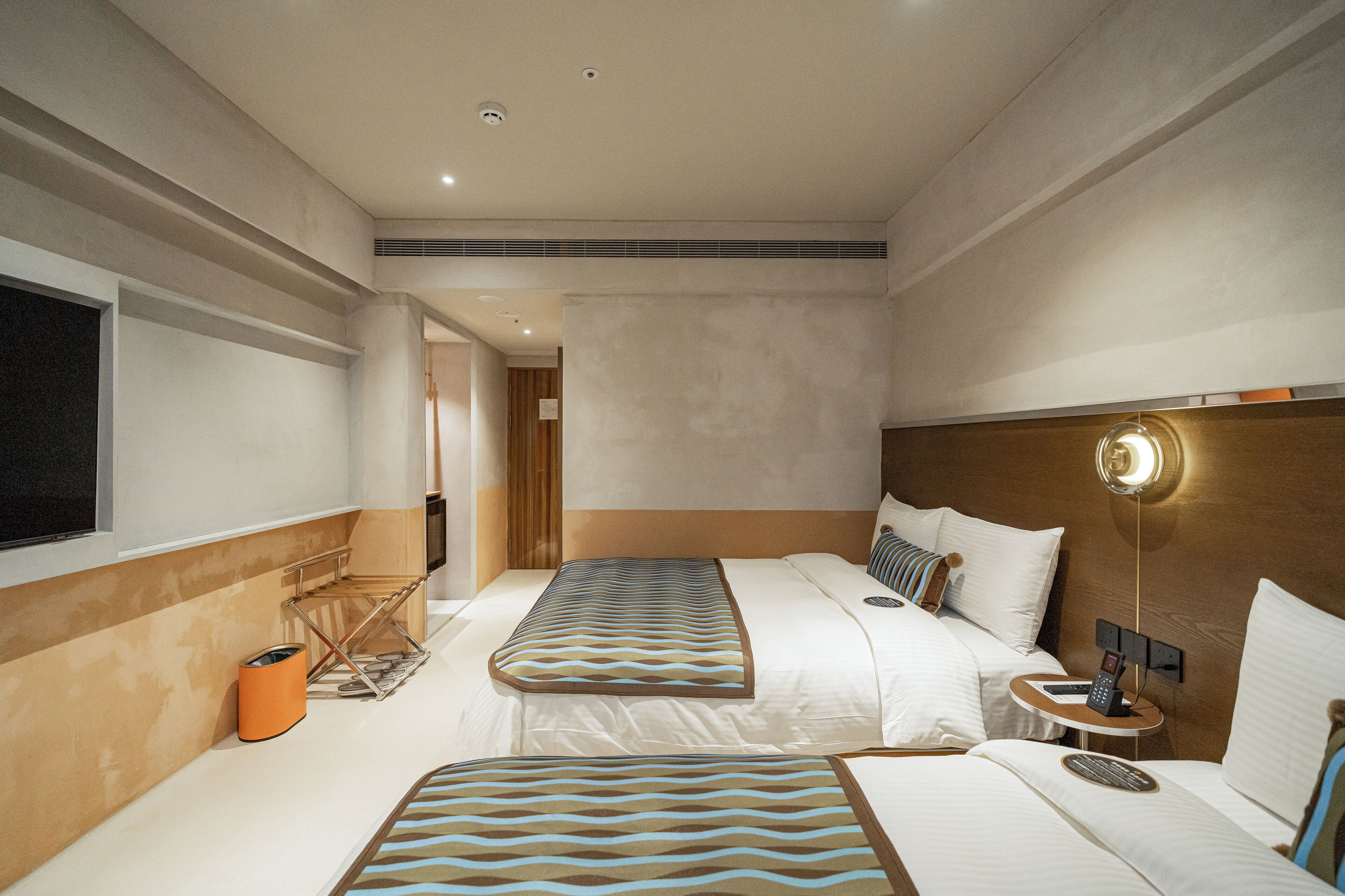 Habitación de hotel con dos camas, una mesita de noche con teléfono y una ventana.