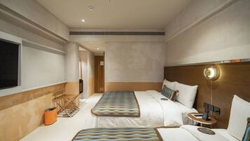 Habitación de hotel con dos camas, una mesita de noche con teléfono y una ventana.