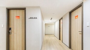 Un pasillo con puertas de madera, cada una con un número y un letrero de seguridad contra incendios.