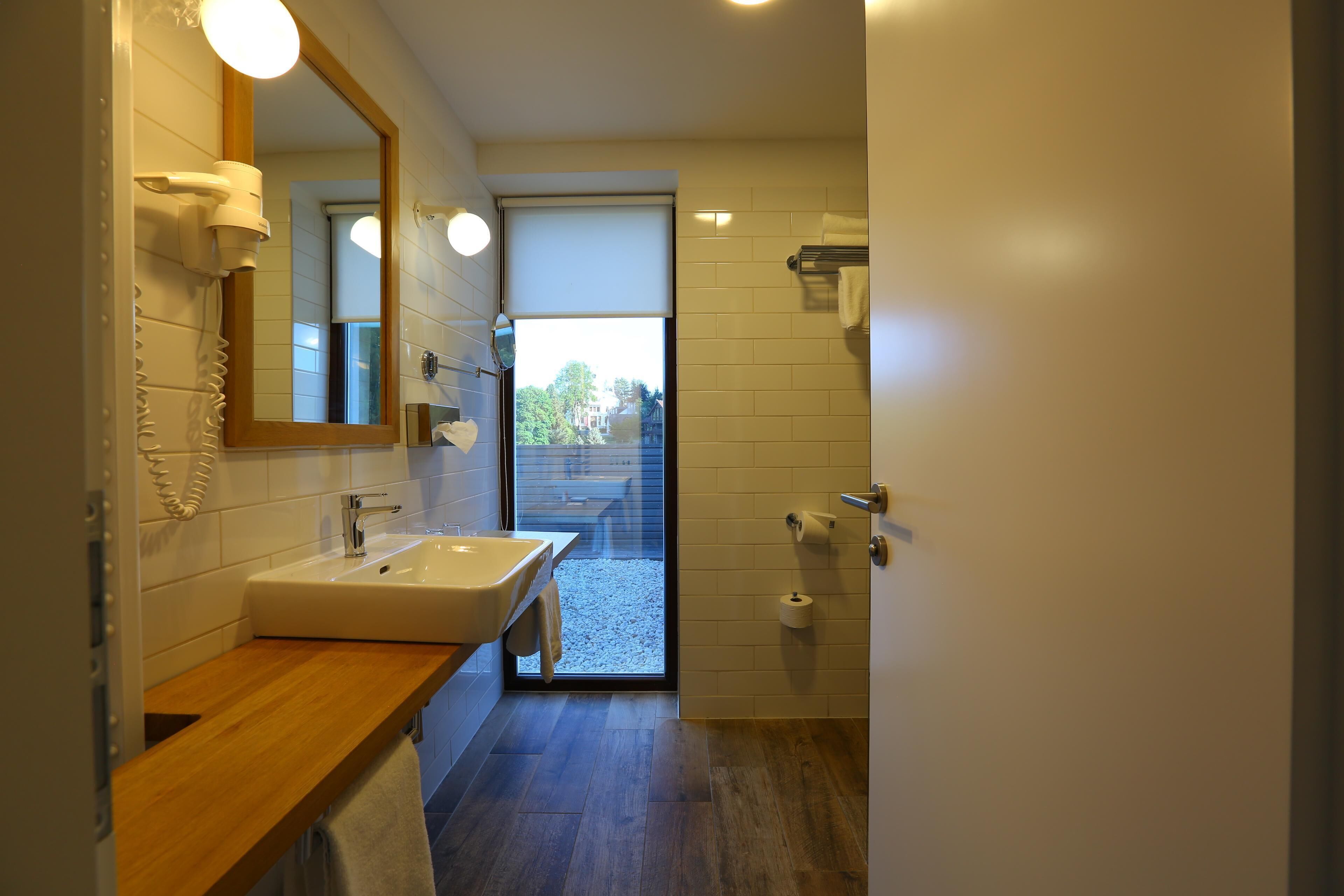A modern bathroom with a wooden vanity, a large mirror, a sink, and a shower area.