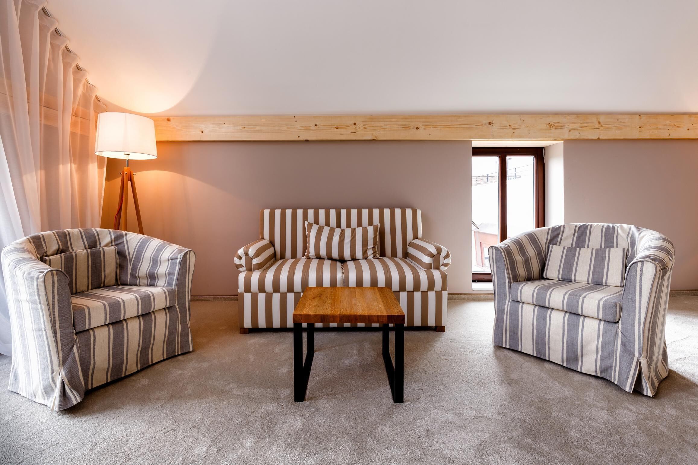 A cozy living room with striped sofas, a wooden coffee table, and a floor lamp.