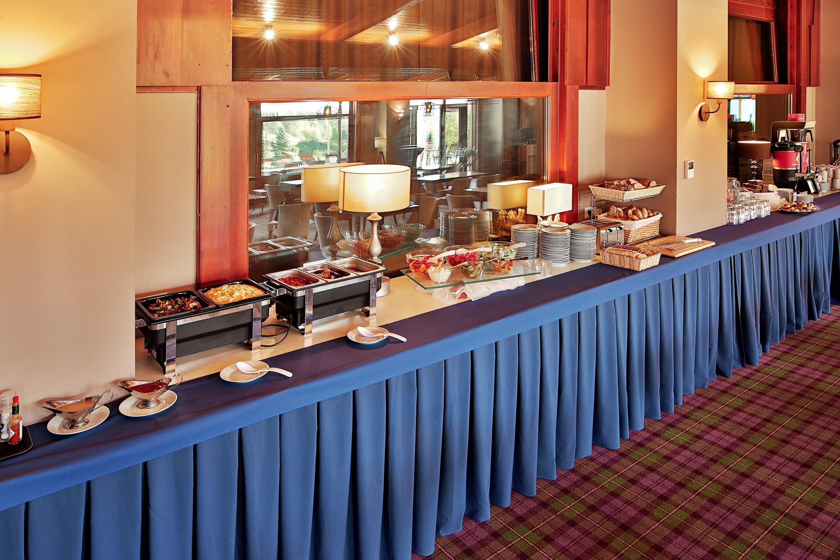 Una mesa de buffet con diversos alimentos y utensilios para servir.