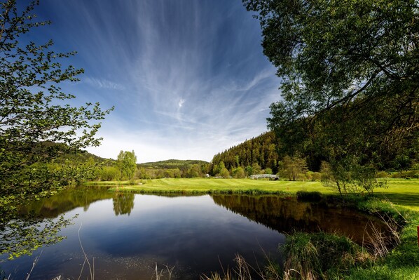 A tranquil lake surrounded by lush greenery and a golf course. - Cihelny Golf & Wellness Resort (Karlovy Vary)