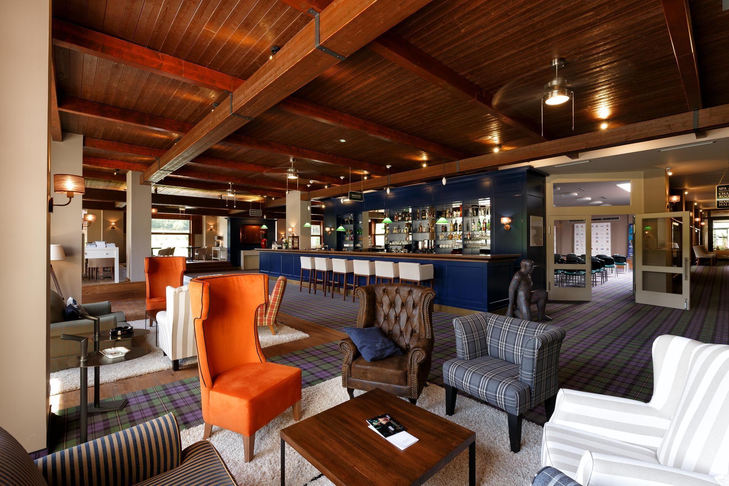 A spacious lobby with a bar area, seating arrangements, and a staircase leading to upper floors.