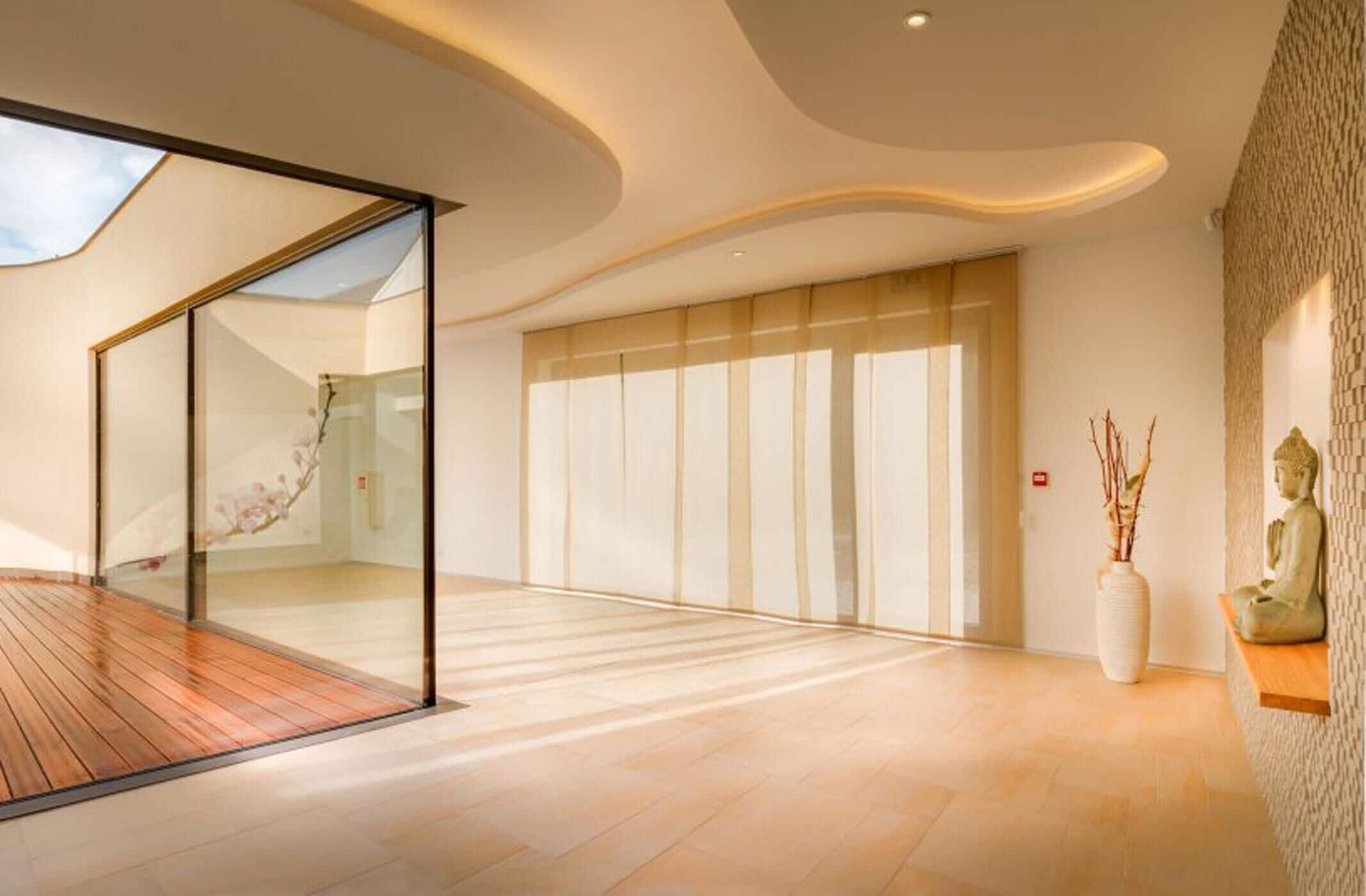 Un interior moderno con piso de madera, paredes de vidrio y un amplio puerta corredera.