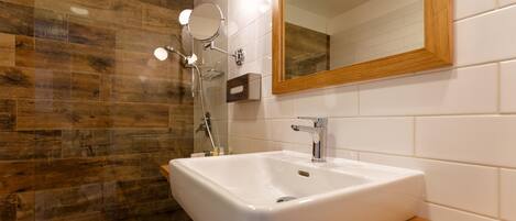 Une salle de bain moderne avec un grand lavabo blanc, un espace de douche en bois et un miroir avec un cadre en bois.