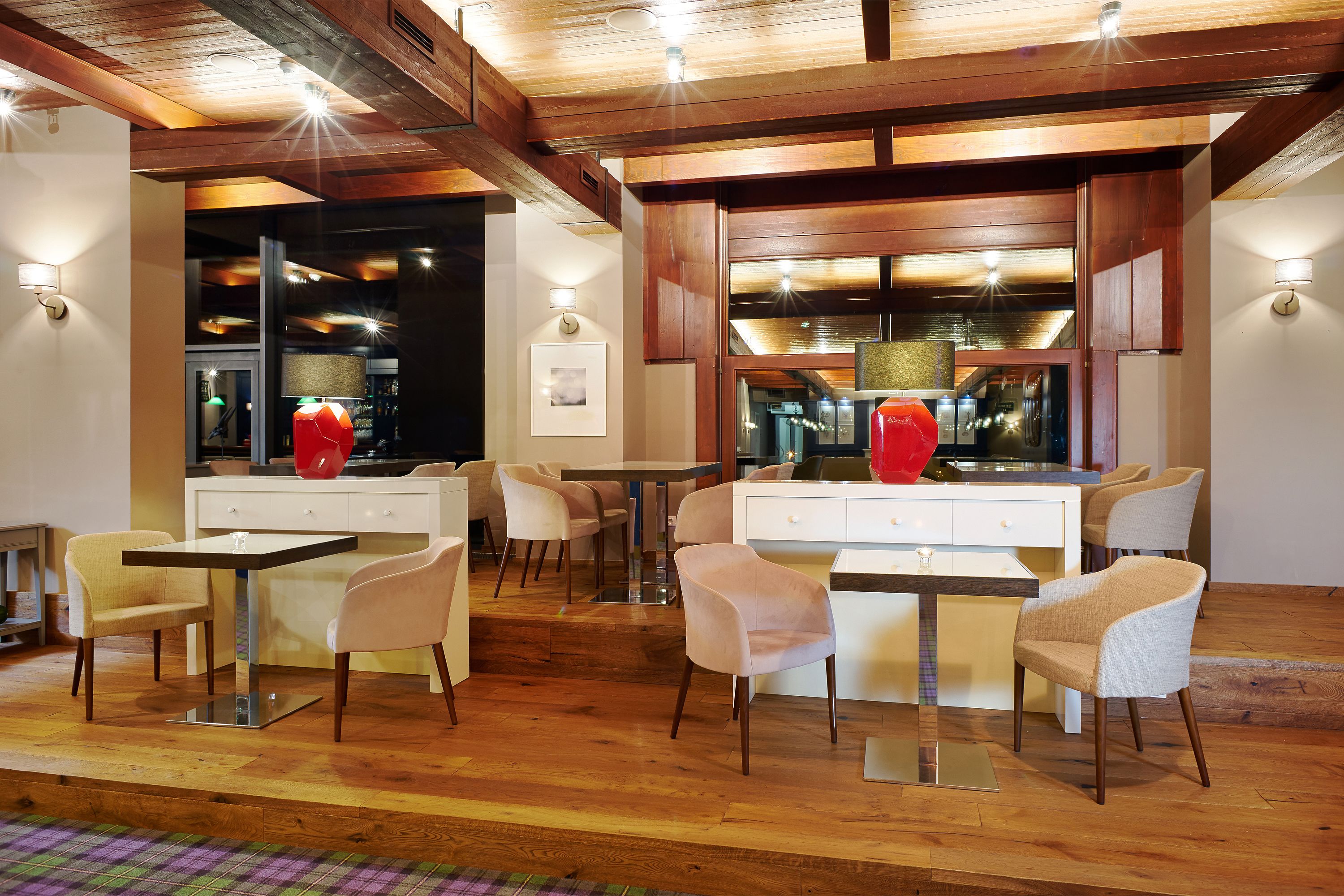 A modern dining area with wooden beams, white furniture, and pendant lighting.