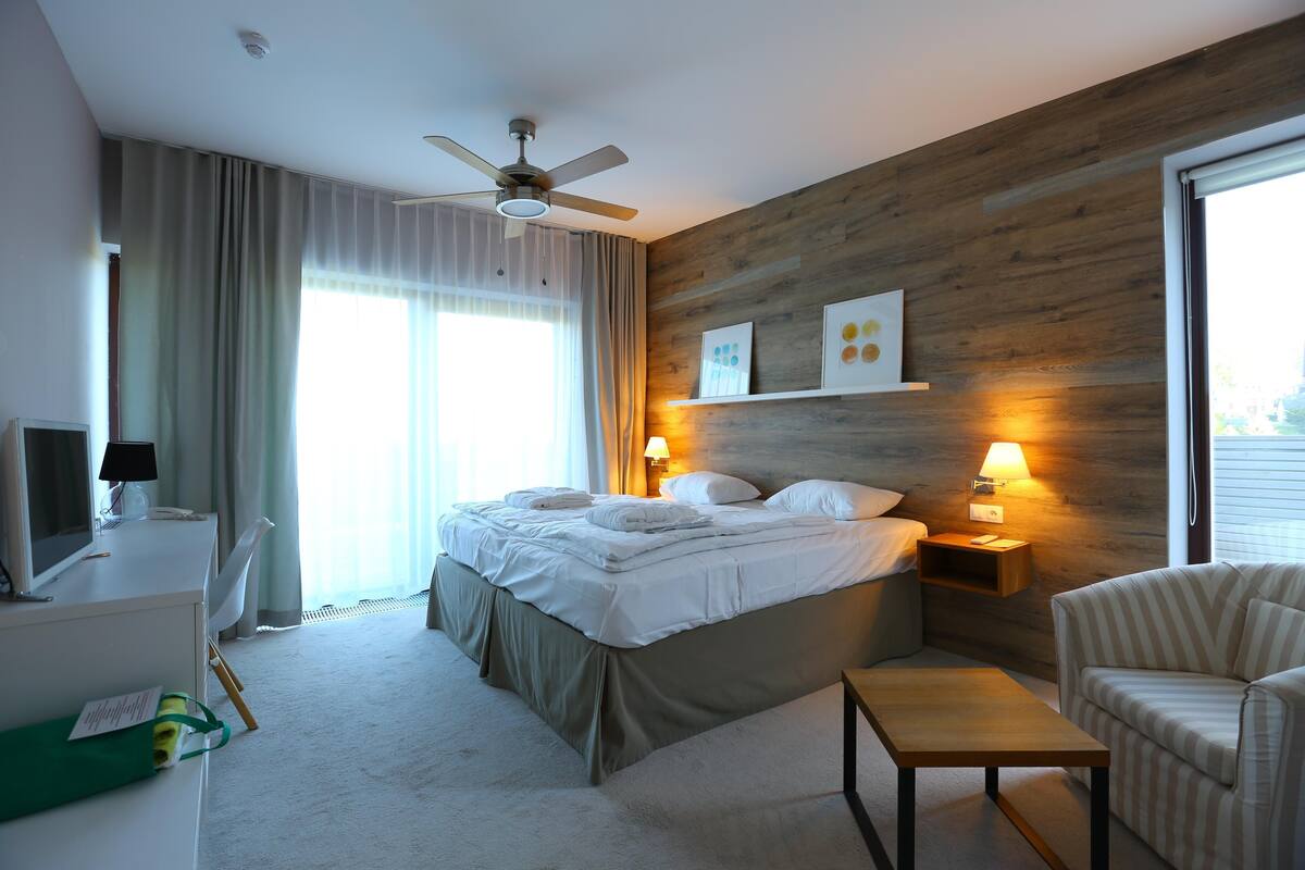 Een moderne hotelkamer met een groot bed, een bureau, een stoel en een klein tafeltje.