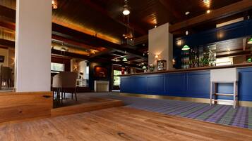 Un espace bar doté d’un plancher en bois, d’un comptoir de bar bleu et d’un éclairage suspendu.