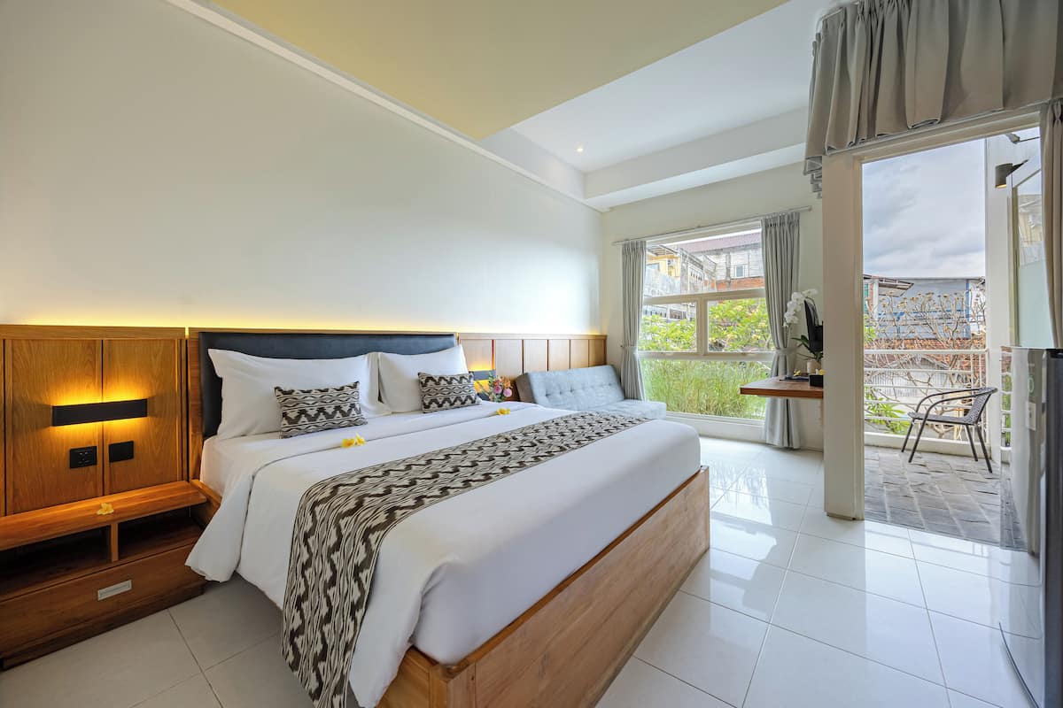 A spacious bedroom with a large bed, wooden headboard, and a view of the outdoor area.