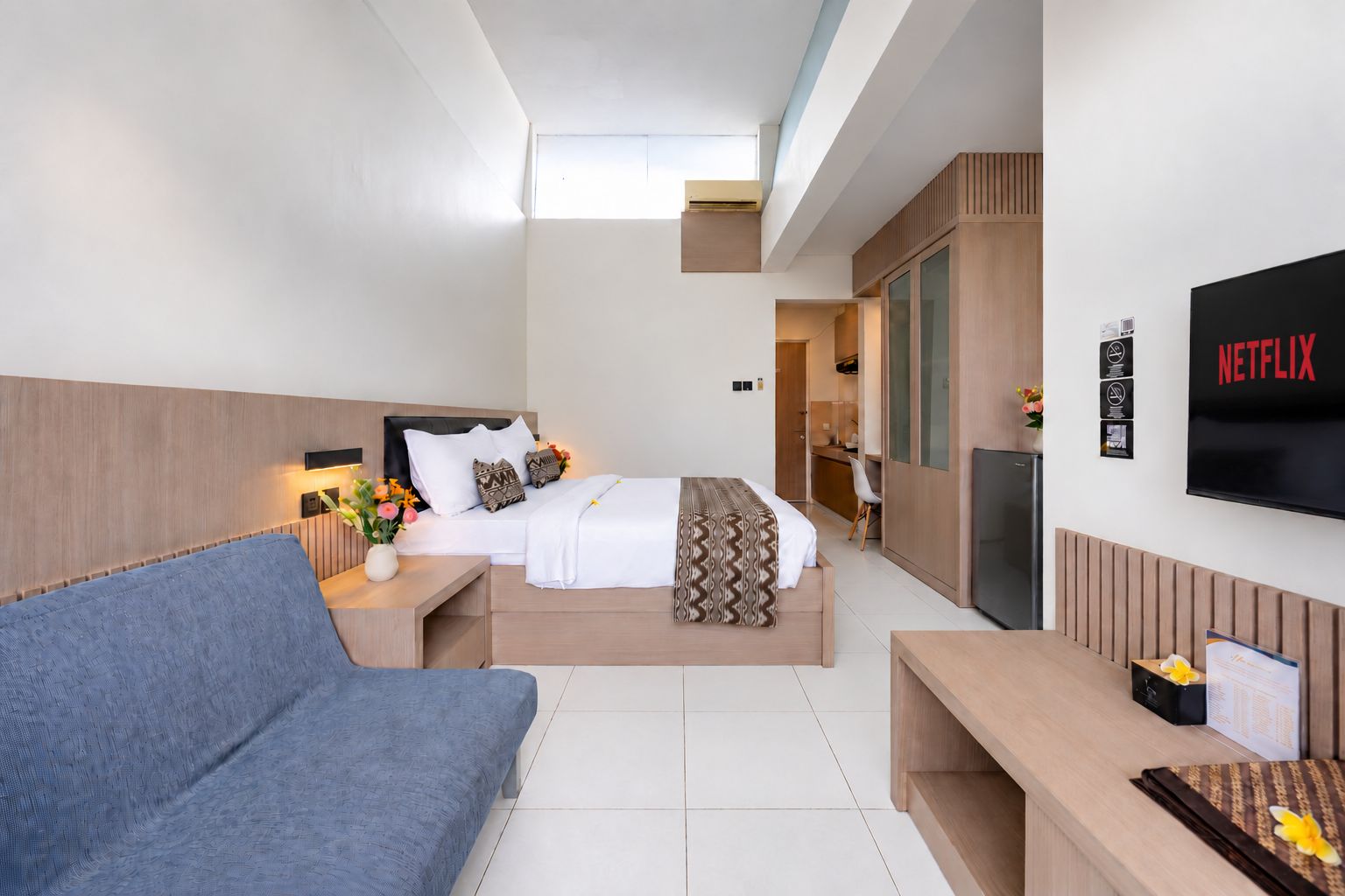 Een moderne hotelkamer met een bed, een bank, een televisie en een bureau.