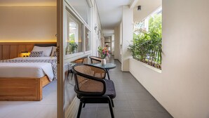 A hotel room with a bed, a small table, chairs, and potted plants. - Bali True Living Apartment (Denpasar)