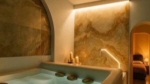 Ett spa-rum med ett stort badkar, en väggmonterad värmare och en säng i det intilliggande rummet.