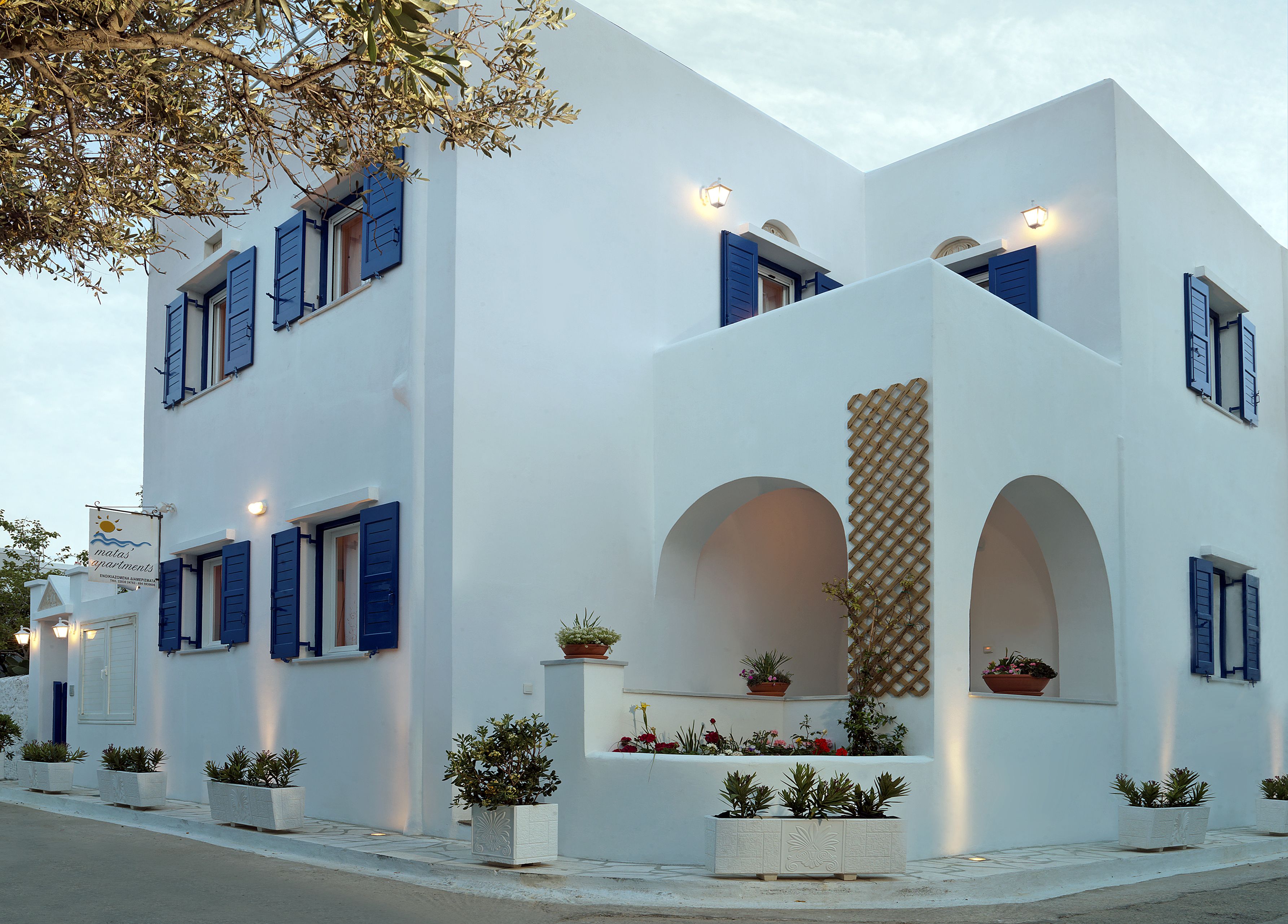 A white building with blue shutters and multiple balconies.