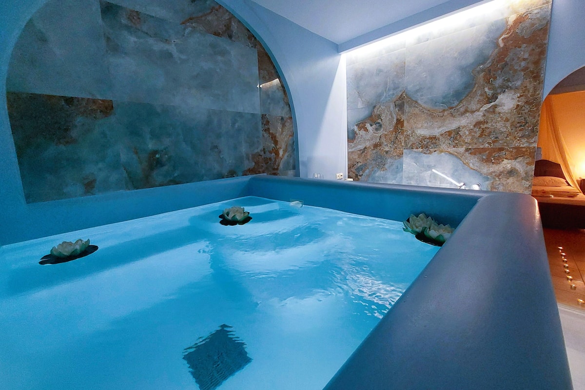 Un moderno spa con una bañera grande, techo abovedado y paredes de mármol.