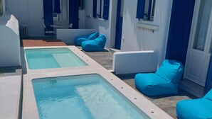 Ett poolområde med två rektangulära pooler och blå sittmöbler.