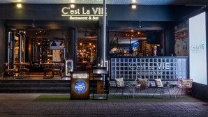 A restaurant named 'C'est La Vie' with outdoor seating and a 'Prost Beer' sign. - Viva Dash Hotel Seminyak (Keroboken Kelod)