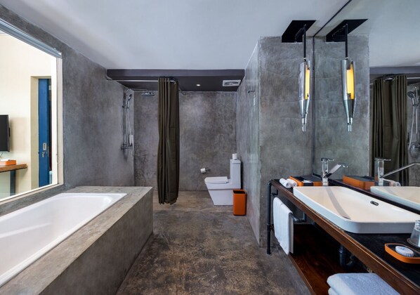 A modern bathroom with a bathtub, two sinks, a shower, and a toilet.