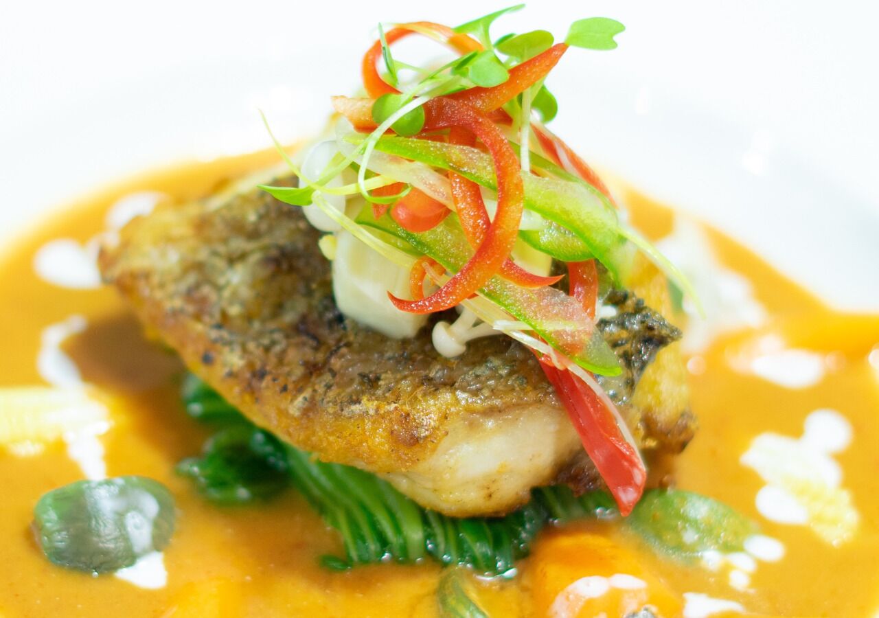Un plato con pescado, verduras y salsa.