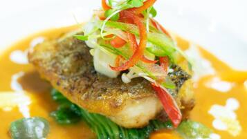 Un plato con pescado, verduras y salsa.