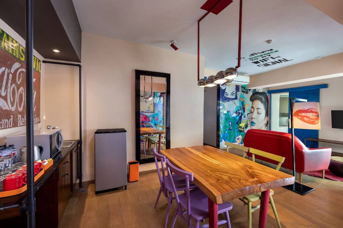 A modern kitchen with a wooden table, purple chairs, and a refrigerator.