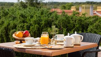 Una mesa de desayuno al aire libre, con vistas a zonas verdes y edificios en el fondo.