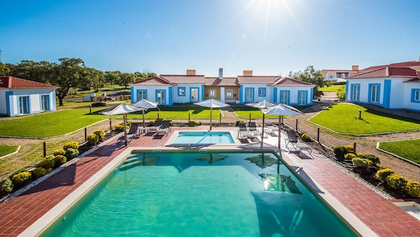 Un resort con una piscina central, varias habitaciones y un césped bien cuidado.