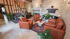 A spacious living room with a stone fireplace, leather sofas, and a variety of plants.