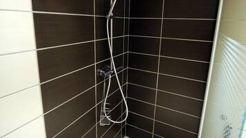 A shower with a handheld showerhead and a wall-mounted faucet.