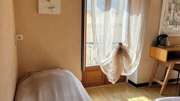 Una habitación con dos camas, un escritorio y una ventana con cortinas traslúcidas.