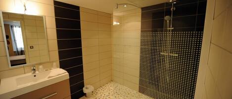 A modern bathroom with a large mirror, a sink, and a shower with a glass door.