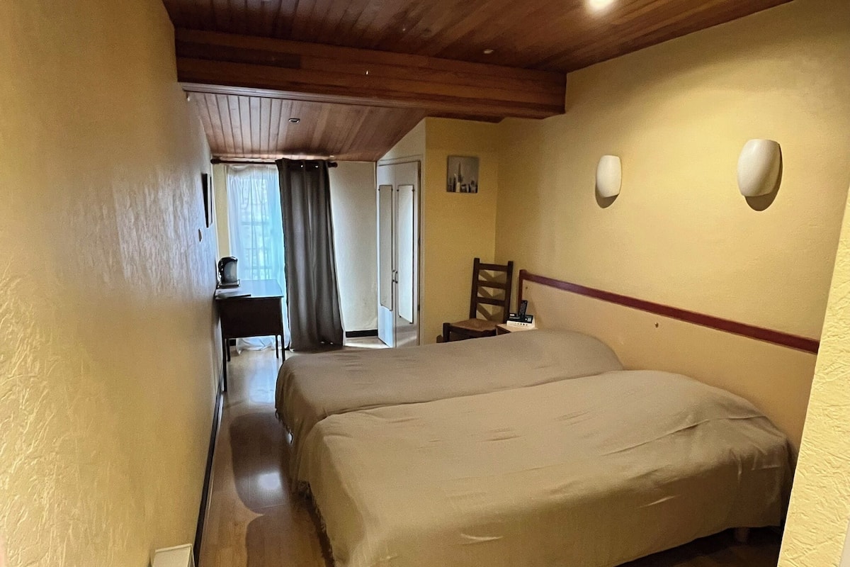 A hotel room with a large bed, a desk with a chair, a small table, and a chair.
