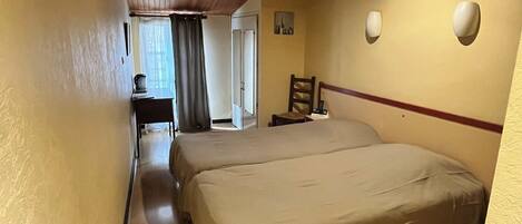 A hotel room with a large bed, a desk with a chair, a small table, and a chair.