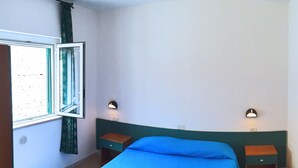 A bedroom with a single bed, two bedside tables, a window with curtains, and wall-mounted lights. - Villaggio Turistico Il Falco (Vieste)
